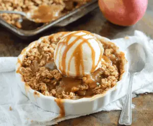 Delicious caramel apple crisp topped with whipped cream and cinnamon, served in a baking dish ready to enjoy