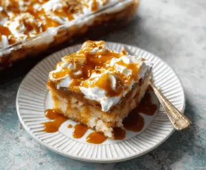 Delicious Caramel Apple Poke Cake topped with caramel drizzle and apple slices, perfect for fall dessert cravings