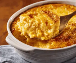 Creamy golden corn pudding in a serving dish topped with fresh herbs, perfect as a comforting side dish