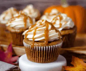 Delicious Pumpkin Caramel Cupcakes topped with whipped cream and caramel drizzle on a festive plate, perfect for fall desserts.