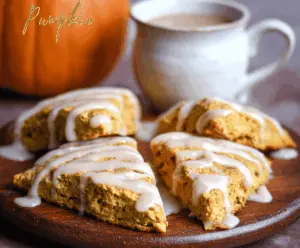 Delicious homemade pumpkin scones topped with creamy maple icing on a rustic wooden table.