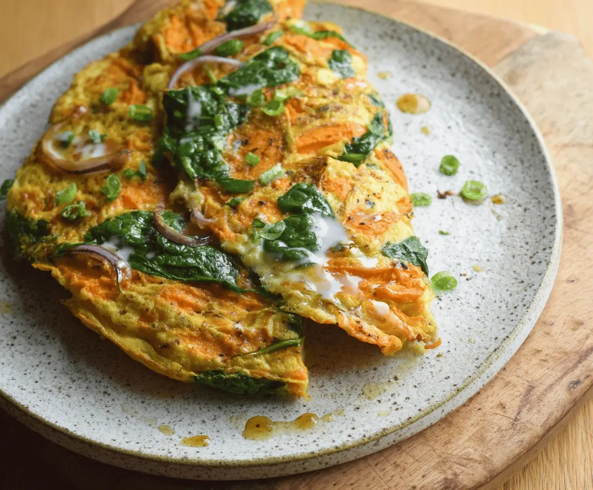 Delicious sweet potato and spinach omelette topped with fresh herbs, served on a plate for a healthy breakfast option