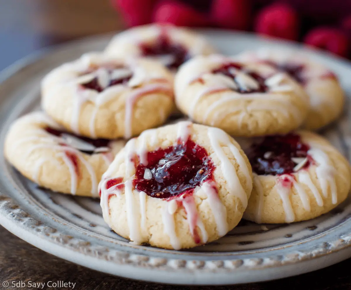 Delicious raspberry jam thumbprint cookie topped with almond glaze, perfect for baking treats.
