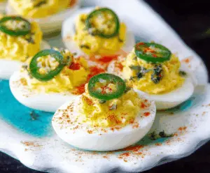 Spicy jalapeño deviled eggs garnished with herbs on a white plate