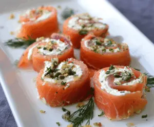 Delicious smoked salmon pinwheels with cream cheese and fresh herbs on a serving platter.