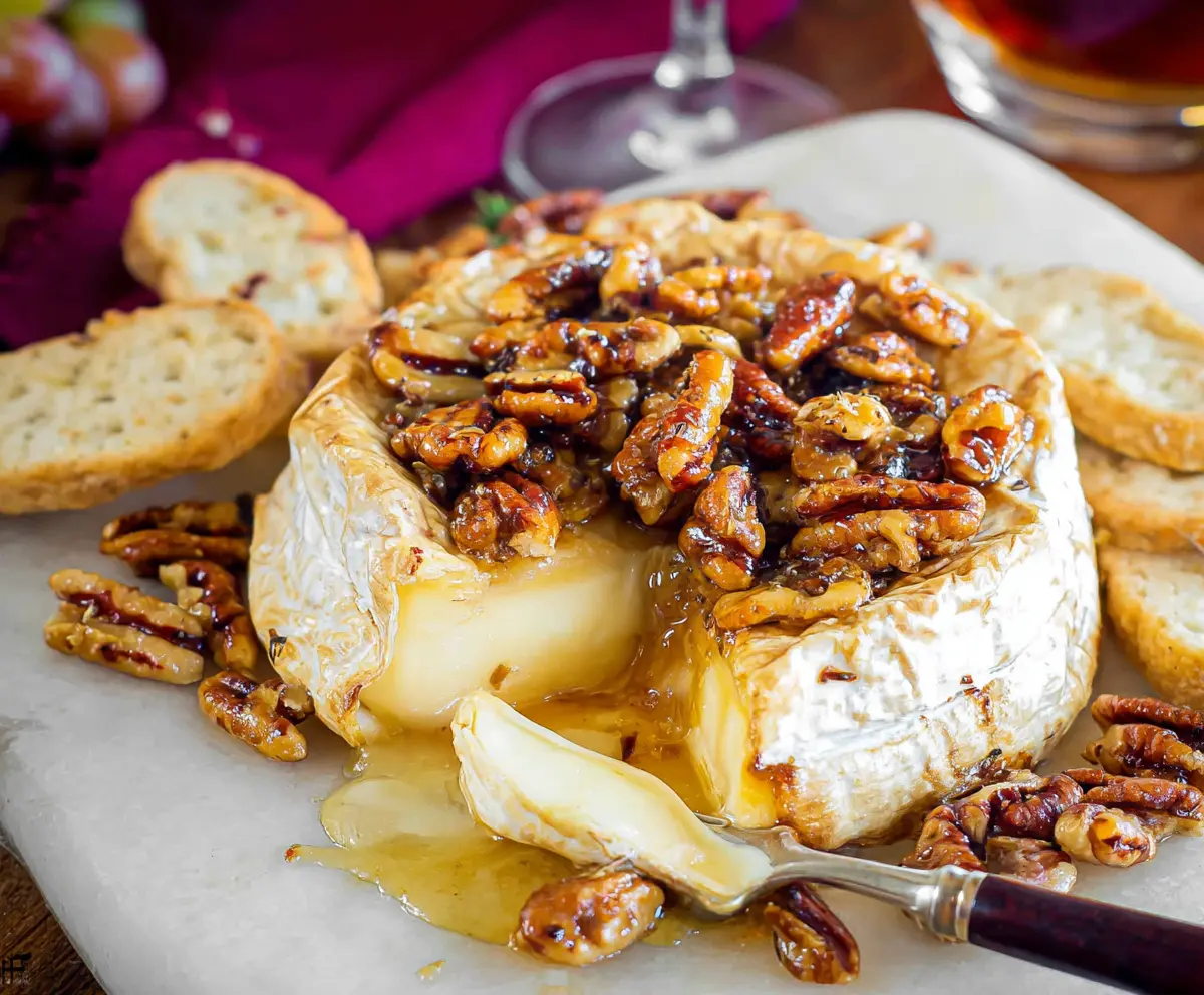 Delicious baked Brie cheese topped with honey and chopped nuts, perfect for appetizers.