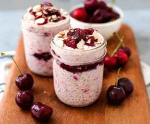 Healthy cherry overnight oats in a glass jar topped with fresh cherries and granola