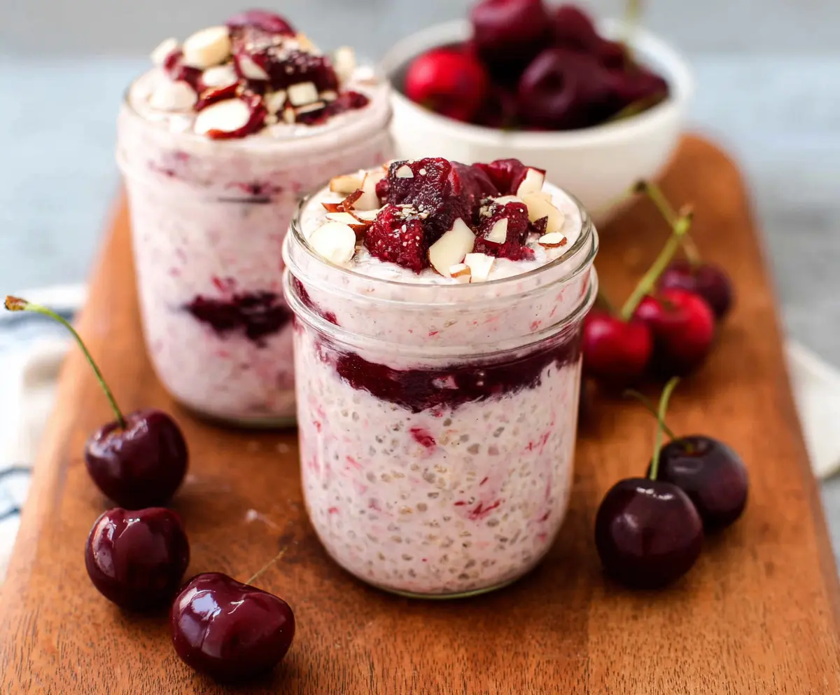 Healthy cherry overnight oats in a glass jar topped with fresh cherries and granola