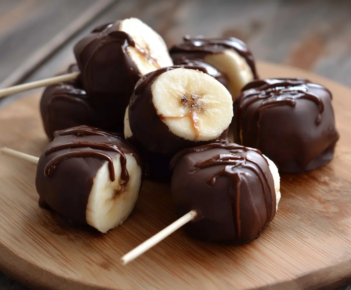 Delicious chocolate covered banana bites on a white plate, perfect for a healthy snack or dessert.