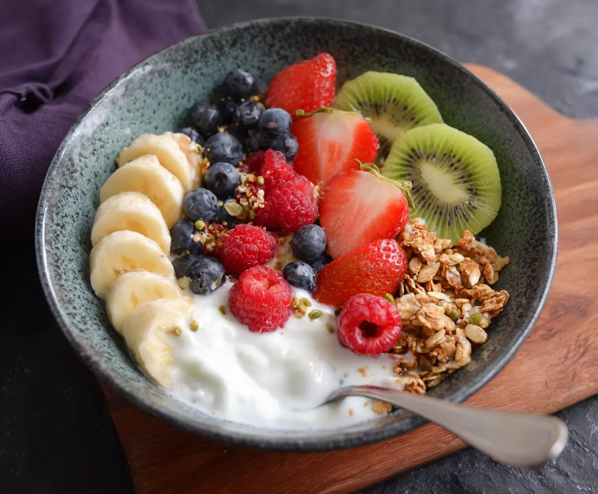 Colorful fruits and creamy yogurt breakfast bowl with blueberries, strawberries, and sliced bananas.