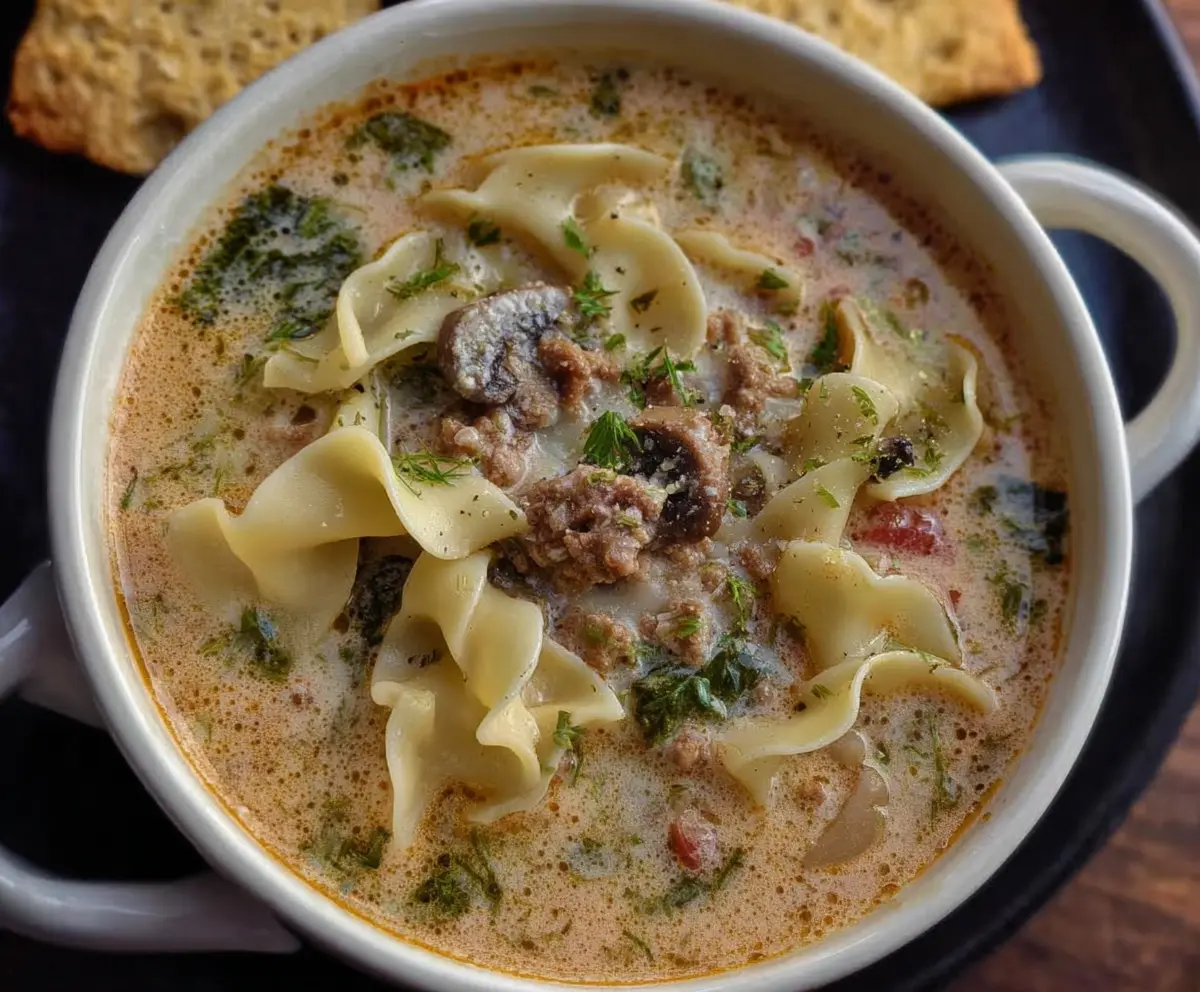 Creamy Alfredo lasagna soup with melted cheese and fresh herbs in a bowl.