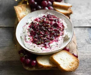 Creamy Cranberry Whipped Boursin Dip with fresh cranberries and herbs served in a white bowl.