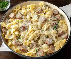 Creamy Sausage Alfredo Pasta served with melted cheese and fresh herbs on a white plate