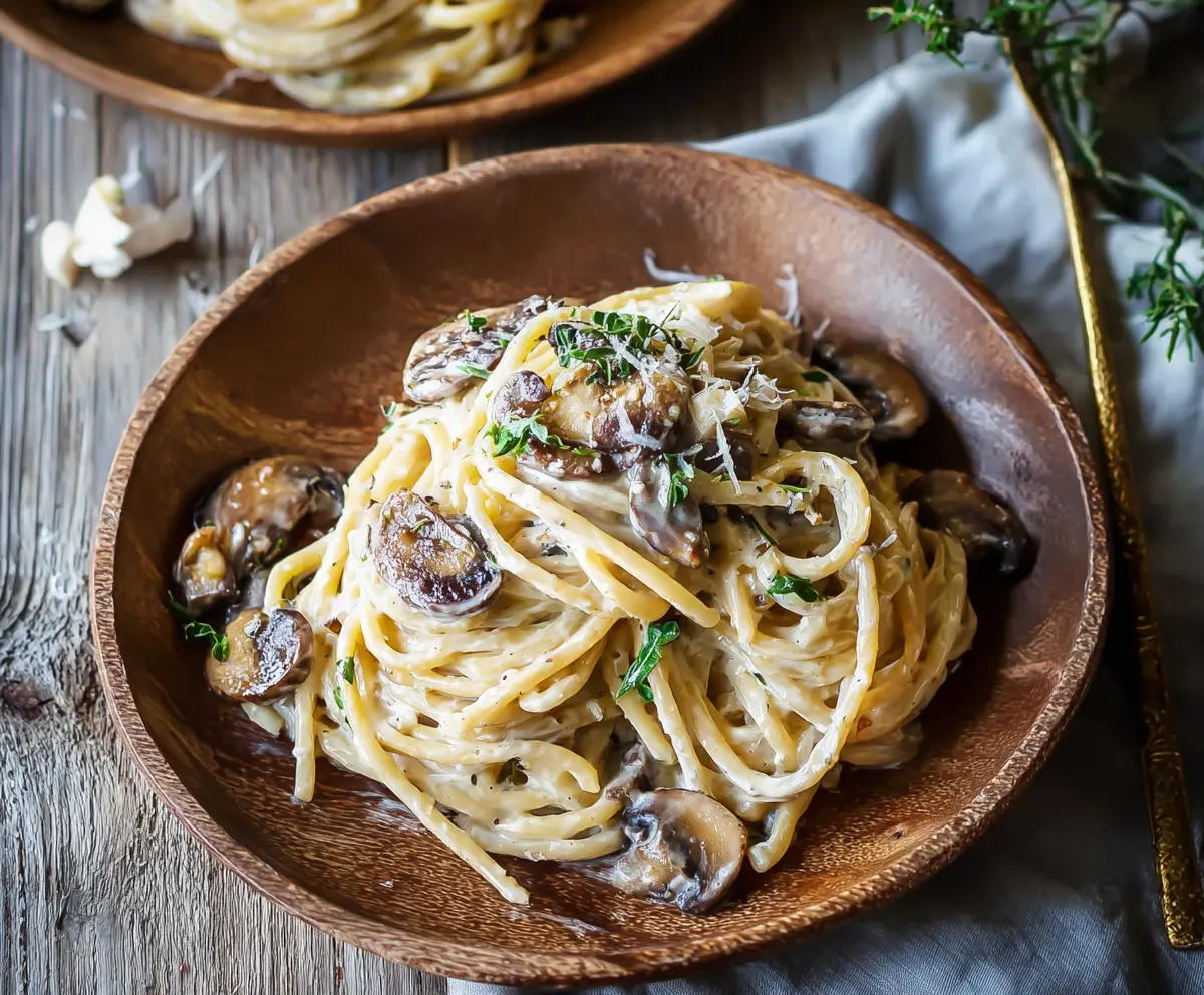 Delicious truffle mushroom cream pasta served on a white plate with fresh herbs.