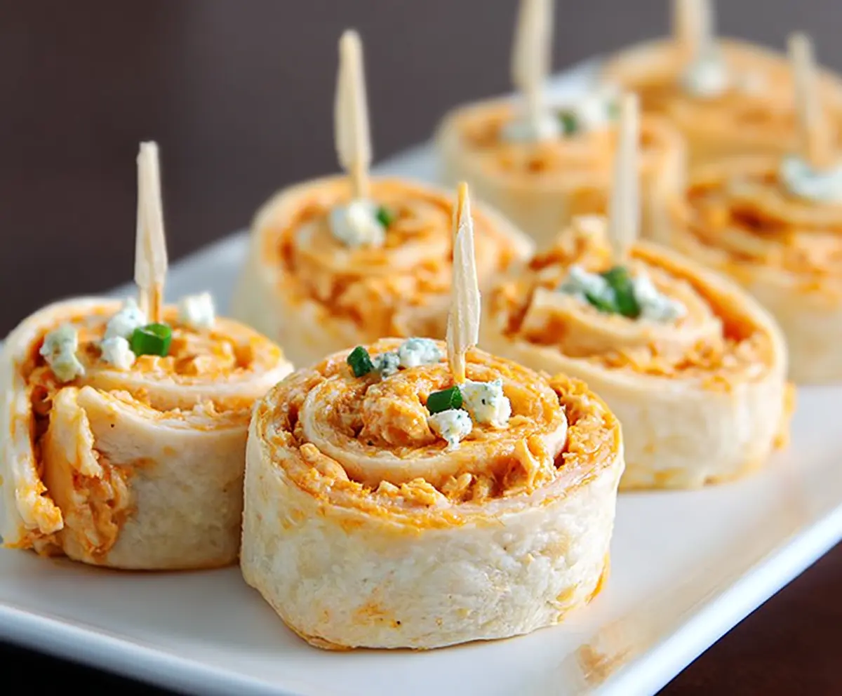 Buffalo chicken pinwheels with creamy cheese filling sliced into rounds for a party appetizer.