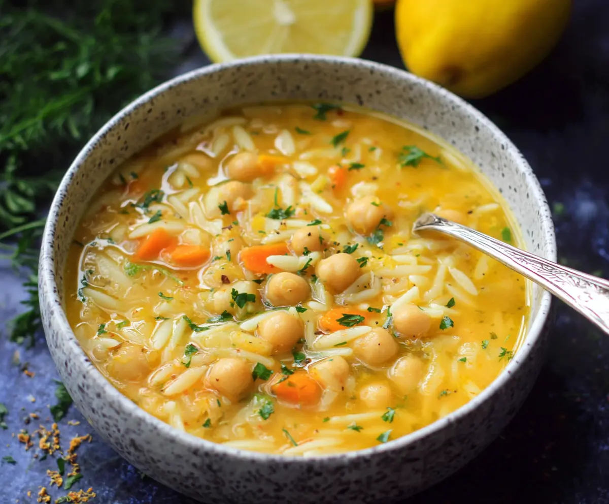 Creamy Lemon Chickpea Orzo Soup in a white bowl garnished with fresh herbs.