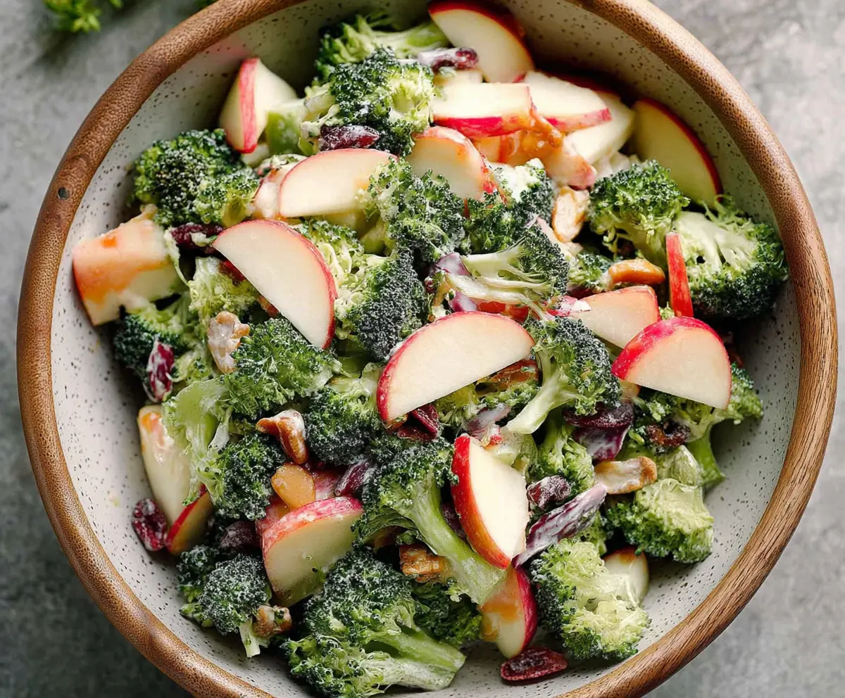 Fresh broccoli and apple salad with nuts and dressing in a bowl, healthy & colorful side dish.