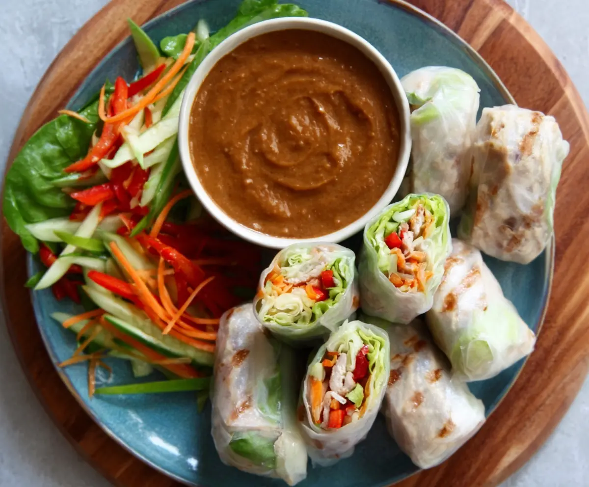 Delicious pork spring rolls with crispy exterior served with vibrant peanut lime sauce.